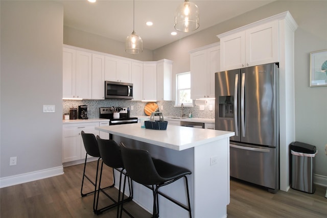 kitchen with a center island, stainless steel appliances, white cabinetry, and dark hardwood / wood-style floors