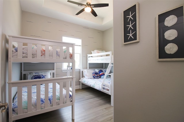 bedroom featuring a tray ceiling, ceiling fan, and hardwood / wood-style floors