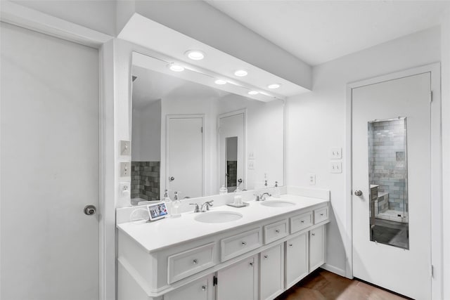 full bath with double vanity, a sink, and recessed lighting