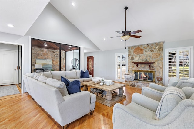 living area with light wood-type flooring, a fireplace, high vaulted ceiling, and a healthy amount of sunlight