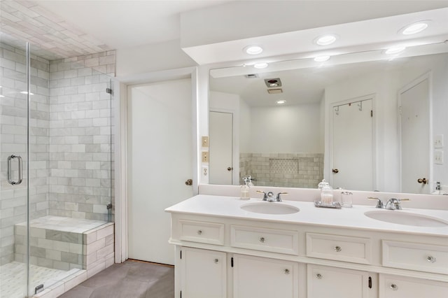 bathroom featuring double vanity, a stall shower, and a sink