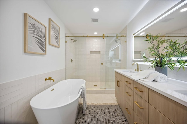 bathroom featuring shower with separate bathtub, vanity, tile patterned floors, and tile walls