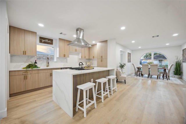 kitchen featuring island exhaust hood, a center island, light hardwood / wood-style floors, and light brown cabinets