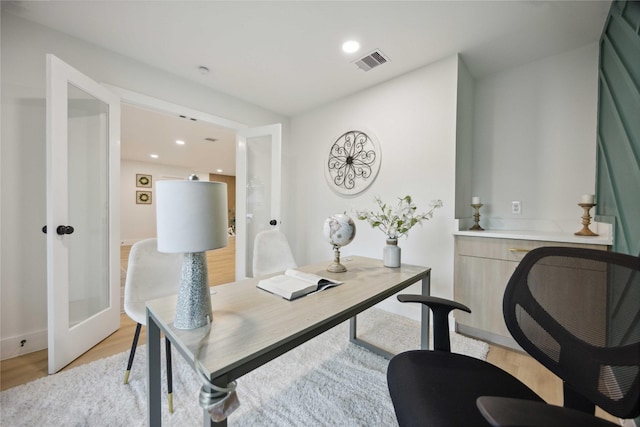 home office with french doors and light hardwood / wood-style flooring