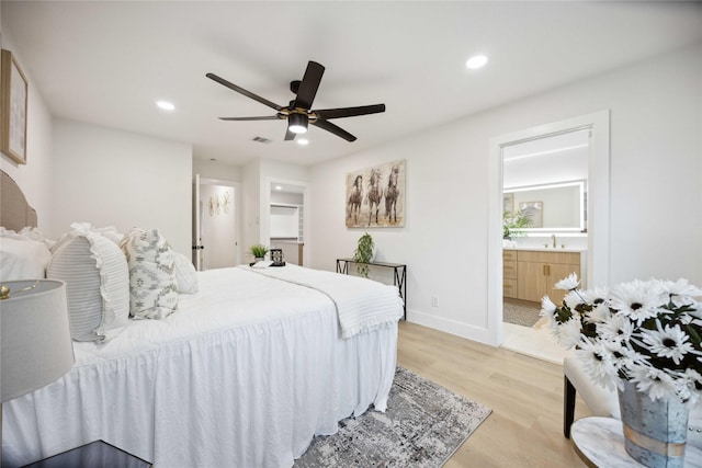 bedroom featuring connected bathroom, light hardwood / wood-style floors, ceiling fan, and sink