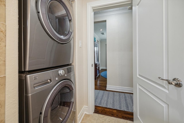 washroom with stacked washing maching and dryer, crown molding, and light tile patterned floors