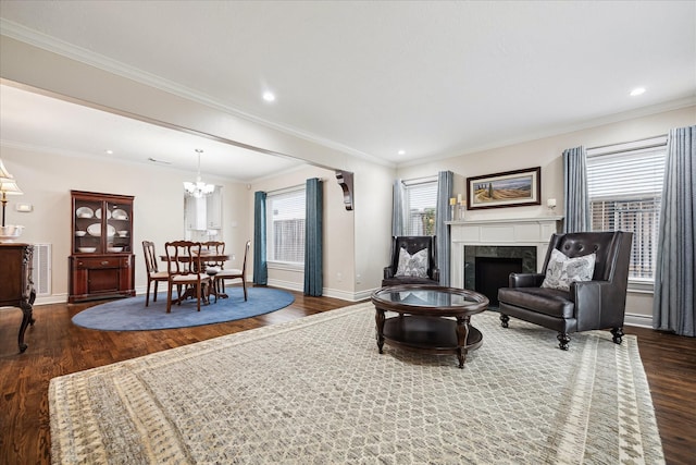 living room featuring a tile fireplace, dark hardwood / wood-style floors, a chandelier, and ornamental molding