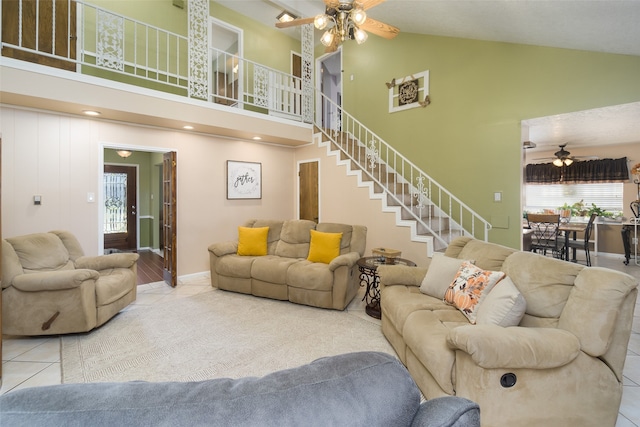 tiled living room with ceiling fan and high vaulted ceiling