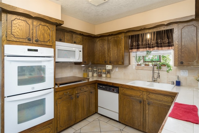 kitchen with a textured ceiling, tasteful backsplash, sink, and white appliances