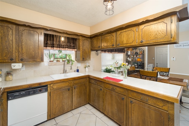 kitchen with dishwasher, plenty of natural light, sink, a textured ceiling, and tile counters