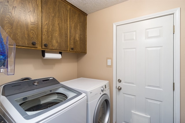 laundry room with washer and dryer, cabinets, and a textured ceiling