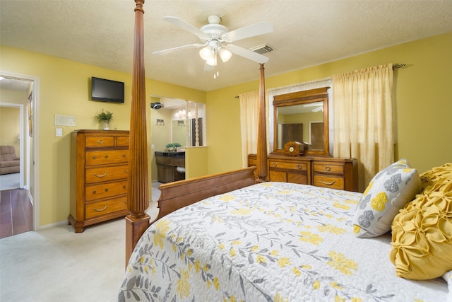 carpeted bedroom with ceiling fan with notable chandelier and a textured ceiling