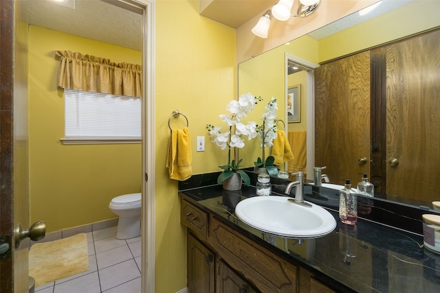 bathroom featuring tile patterned flooring, vanity, toilet, and a textured ceiling