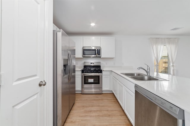 kitchen featuring white cabinets, stainless steel appliances, light hardwood / wood-style flooring, and sink