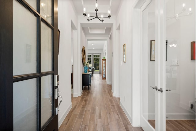 corridor with french doors and an inviting chandelier