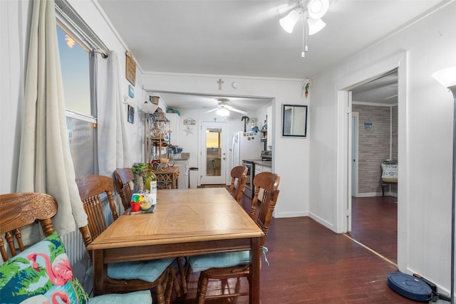 dining space featuring ceiling fan, dark wood-type flooring, and brick wall