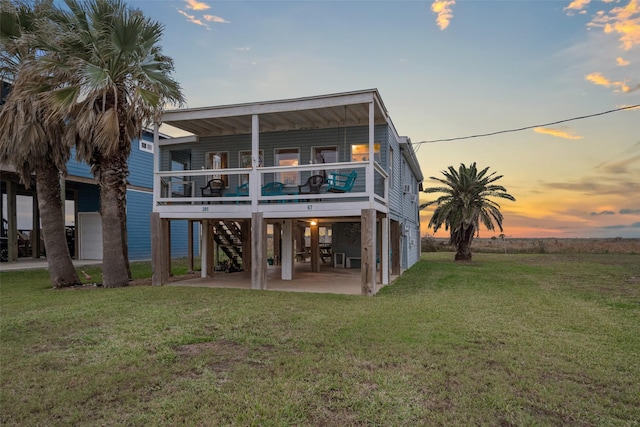 back house at dusk featuring a yard, a balcony, and a patio area