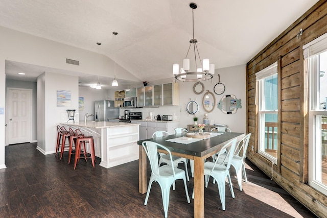 dining space featuring dark wood-type flooring, a chandelier, lofted ceiling, and sink