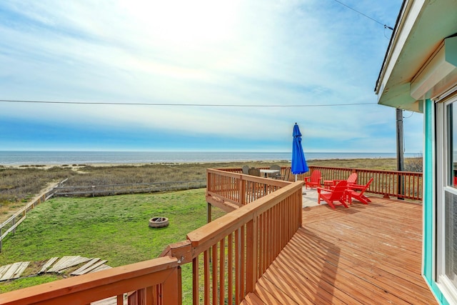 wooden deck with a view of the beach, a yard, and a water view