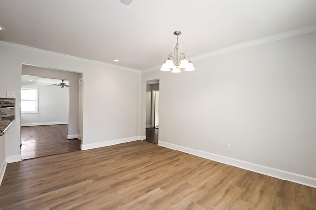 empty room with wood-type flooring, ornamental molding, and a notable chandelier