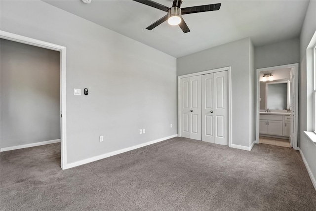 unfurnished bedroom featuring ceiling fan, a closet, ensuite bathroom, and dark colored carpet