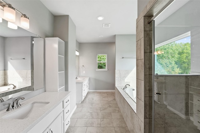 bathroom featuring plus walk in shower, vanity, and tile patterned flooring