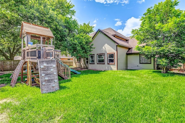 back of property with a lawn and a playground