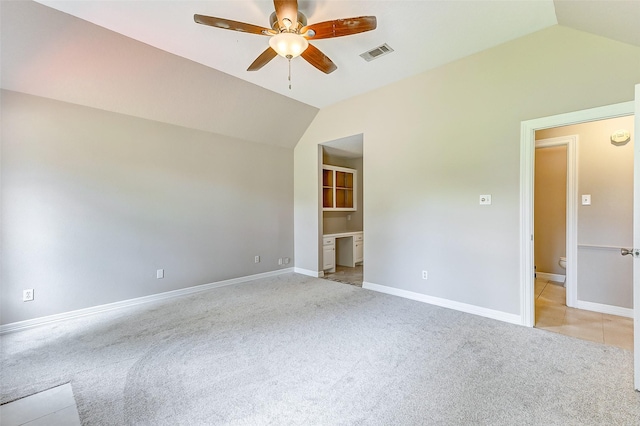 interior space featuring ceiling fan, light colored carpet, lofted ceiling, and ensuite bath