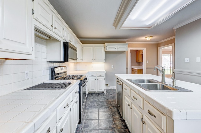 kitchen with appliances with stainless steel finishes, backsplash, sink, tile countertops, and white cabinetry