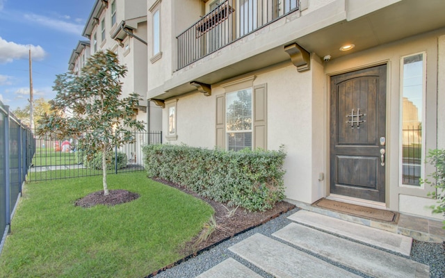 entrance to property with a balcony and a lawn