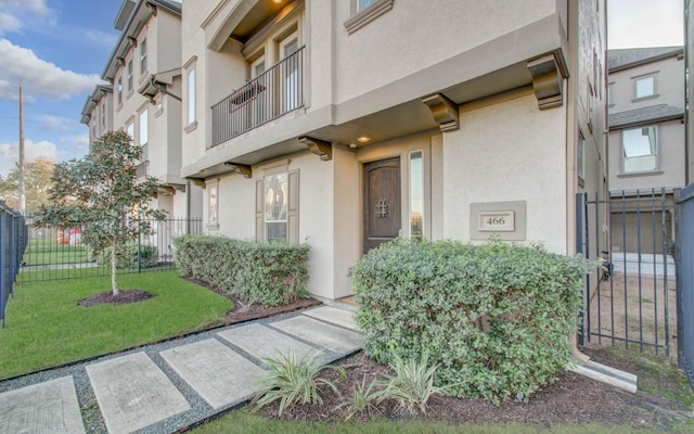 entrance to property with a balcony and a lawn