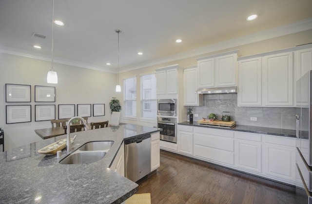 kitchen featuring pendant lighting, backsplash, dark stone countertops, white cabinetry, and stainless steel appliances