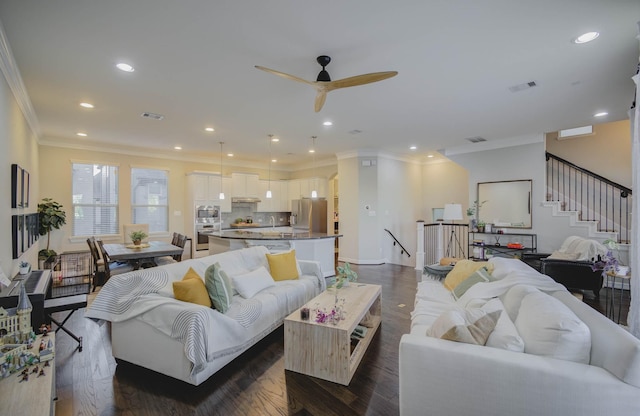 living room with dark wood-type flooring, ceiling fan, and crown molding