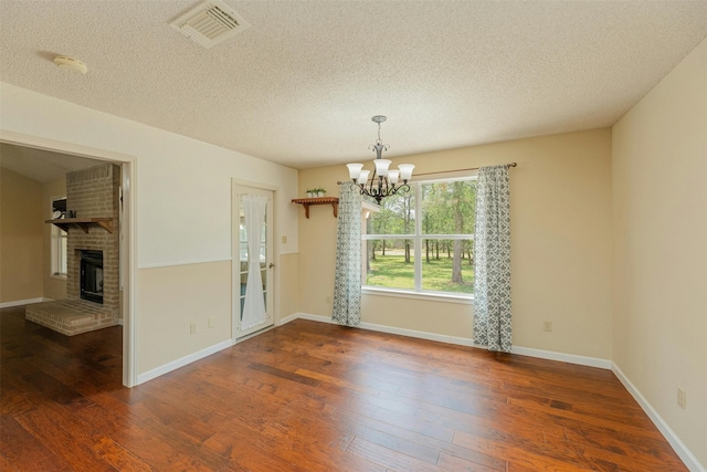 interior space with dark hardwood / wood-style floors, a fireplace, a textured ceiling, and an inviting chandelier