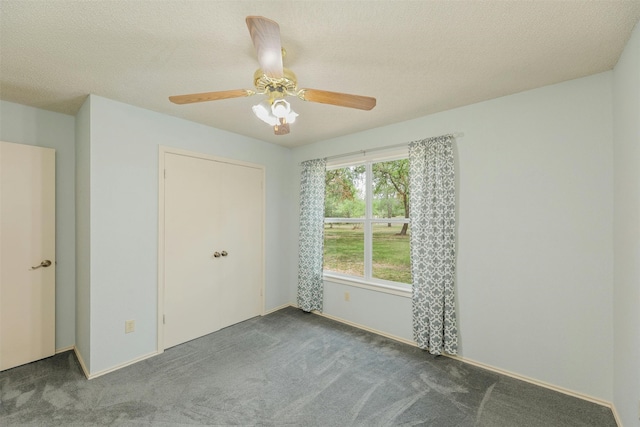 unfurnished bedroom featuring ceiling fan, a closet, dark carpet, and a textured ceiling