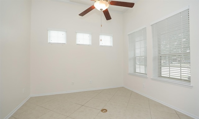 tiled empty room with ceiling fan and plenty of natural light