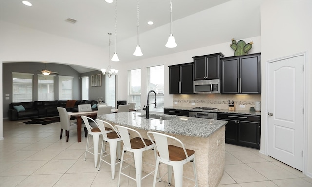 kitchen with lofted ceiling, stainless steel appliances, a kitchen island with sink, and sink