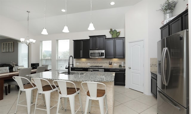 kitchen featuring decorative light fixtures, a center island with sink, tasteful backsplash, appliances with stainless steel finishes, and sink