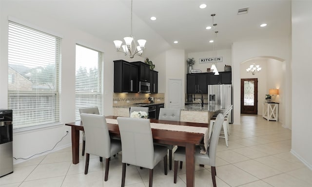 tiled dining area featuring an inviting chandelier and vaulted ceiling