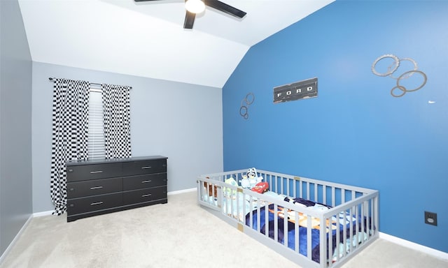 bedroom with lofted ceiling, light colored carpet, ceiling fan, and a crib