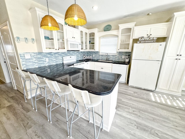 kitchen featuring kitchen peninsula, white appliances, sink, pendant lighting, and white cabinets