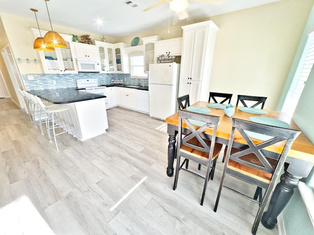 kitchen with tasteful backsplash, a breakfast bar, white appliances, decorative light fixtures, and white cabinetry