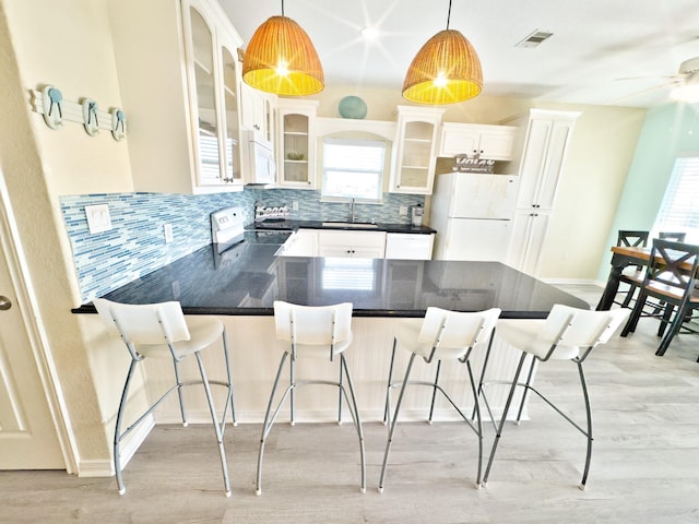 kitchen featuring sink, decorative light fixtures, white appliances, a kitchen bar, and white cabinets