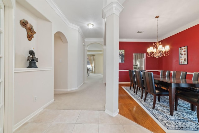 dining area with a chandelier, decorative columns, light tile patterned floors, and crown molding