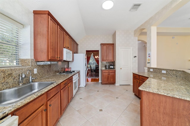 kitchen featuring white appliances, tasteful backsplash, light stone countertops, and sink