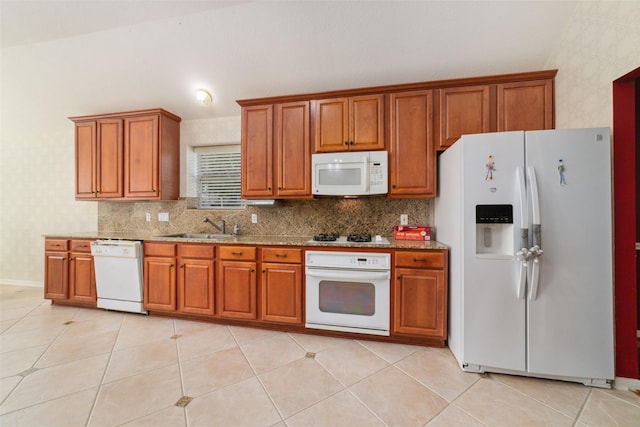 kitchen featuring white appliances, light stone countertops, sink, and light tile patterned floors