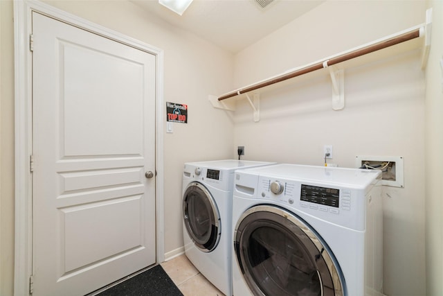 clothes washing area with washer and dryer and light tile patterned flooring