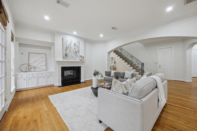 living room with light wood-type flooring and crown molding