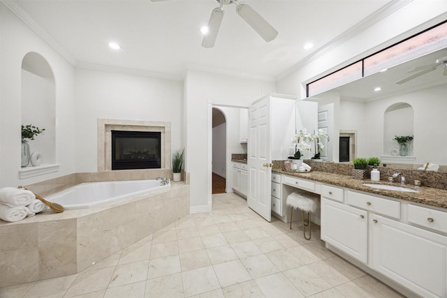 bathroom featuring vanity, tiled bath, ceiling fan, and ornamental molding