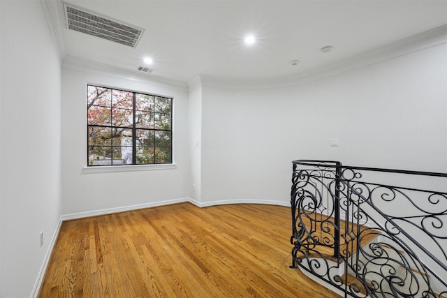 spare room with light wood-type flooring and ornamental molding